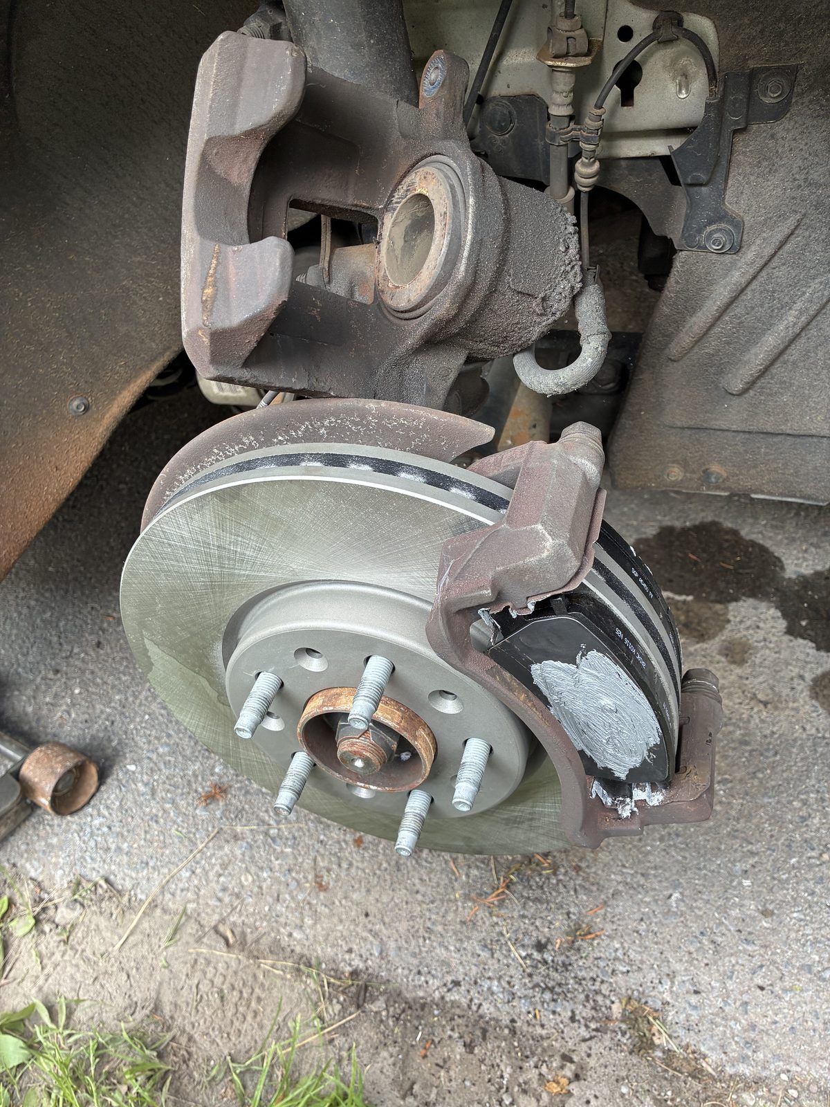 Freshly installed brake rotor, caliper and new pads after service