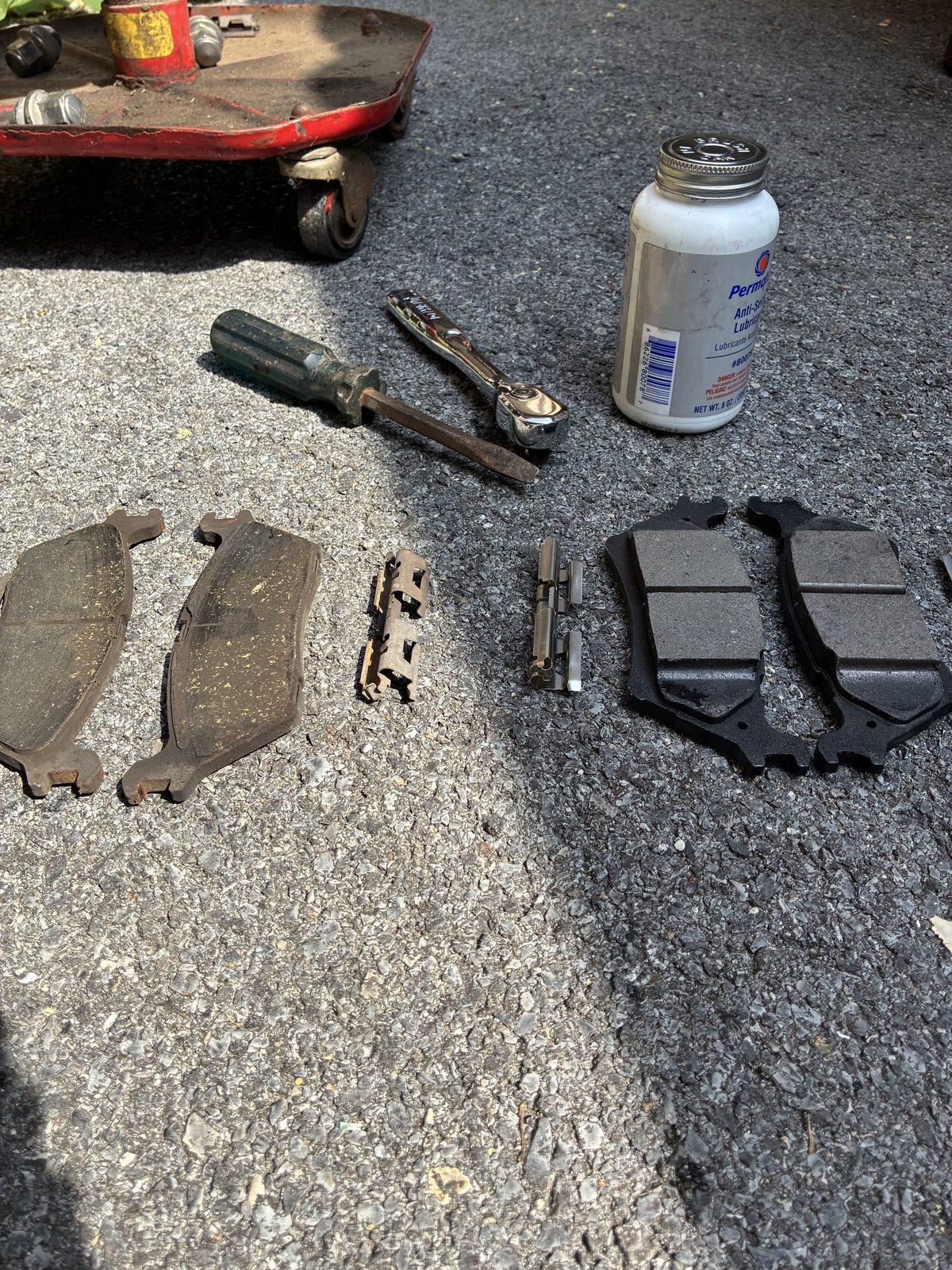 Mobile mechanic carrying tools to a customer's car with the hood up in a driveway